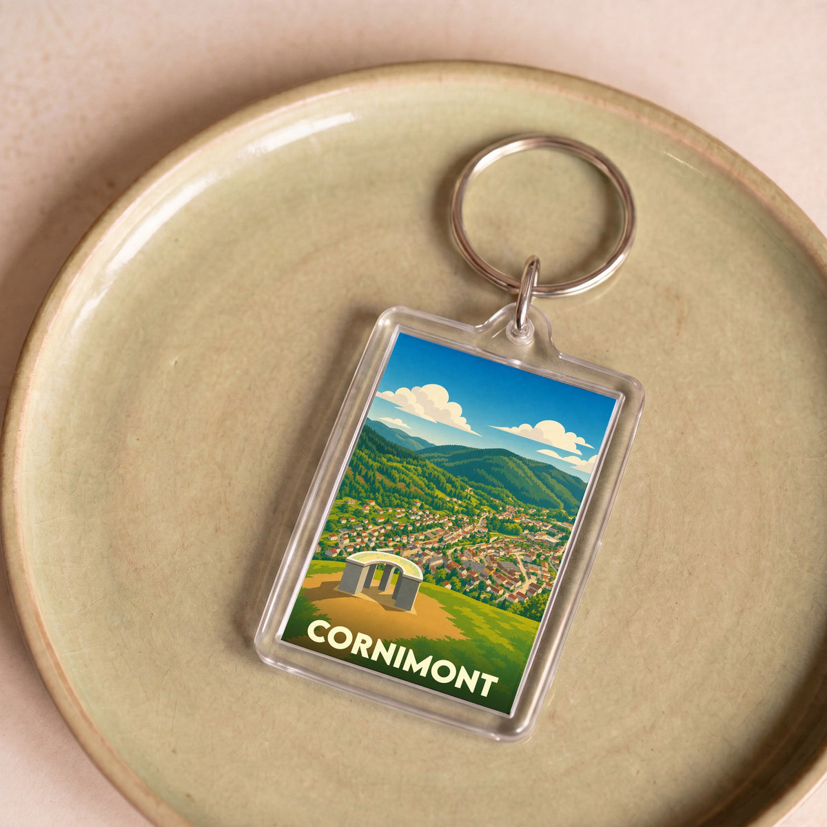 Porte-clés souvenir de la ville de Cornimont avec une illustration stylisée de son paysage montagneux.