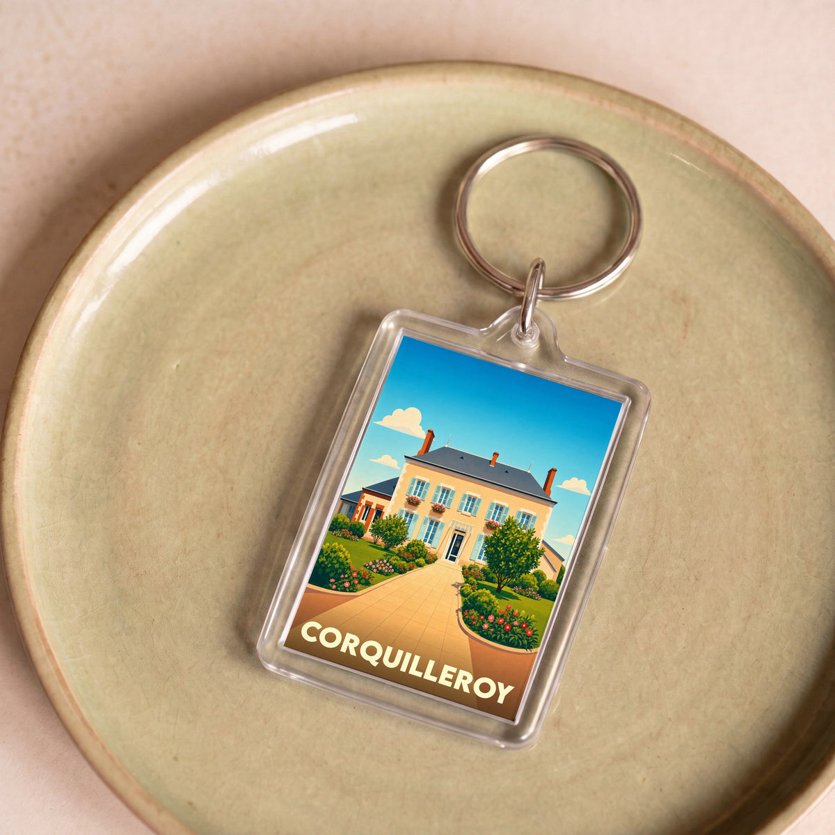 Porte-clés souvenir de la ville de Corquilleroy avec une illustration stylisée d'une maison bourgeoise fleurie.