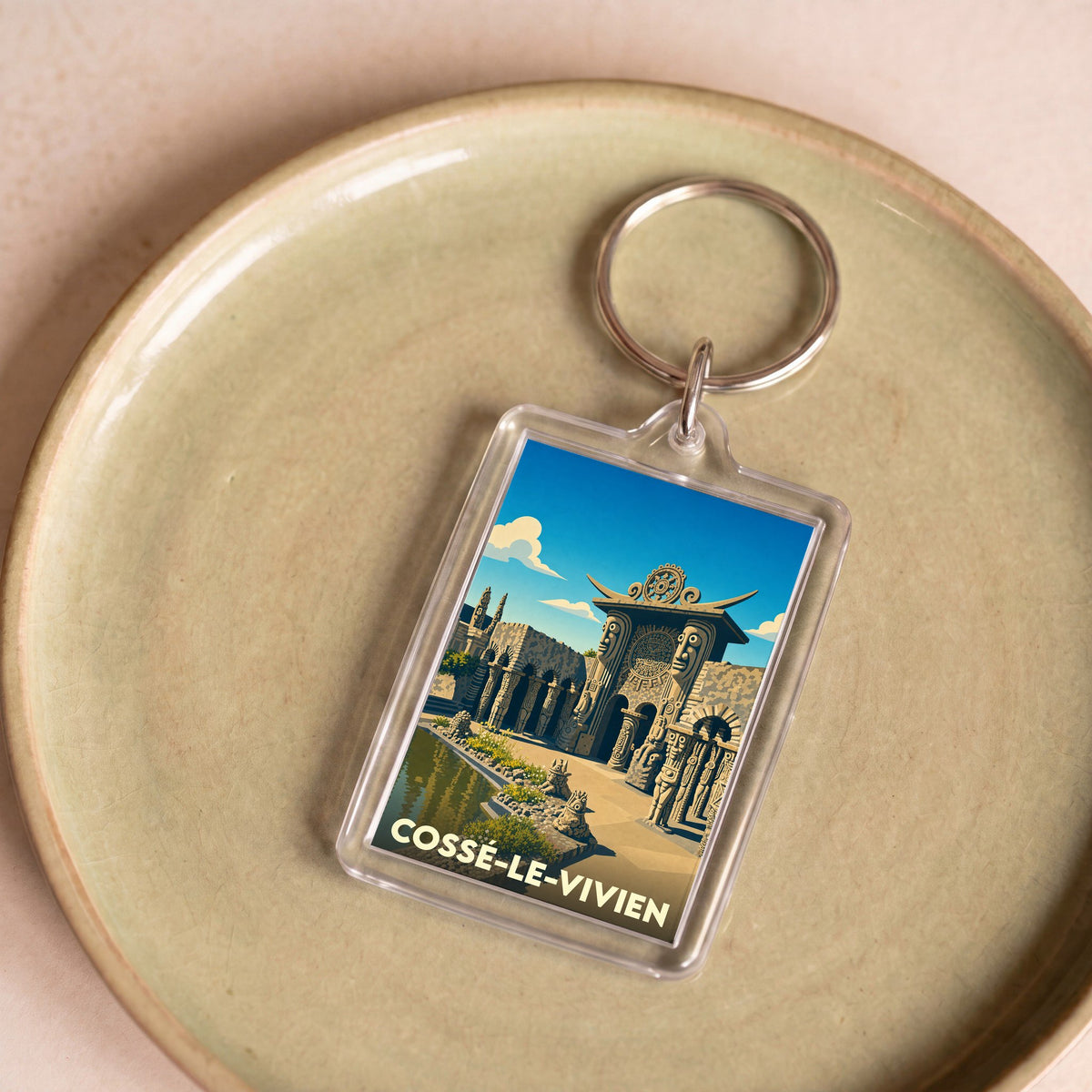 Porte-clés souvenir de la ville de Cossé-le-Vivien avec une illustration stylisée du Musée Robert Tatin.
