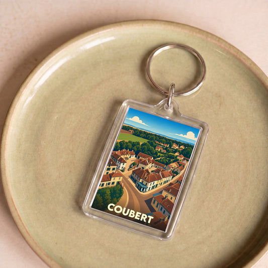 Porte-clés souvenir de la ville de Coubert avec une illustration stylisée d'une vue aérienne du village.