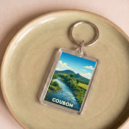 Porte-clés souvenir de la ville de Coubon avec une illustration stylisée d'un paysage de rivière.