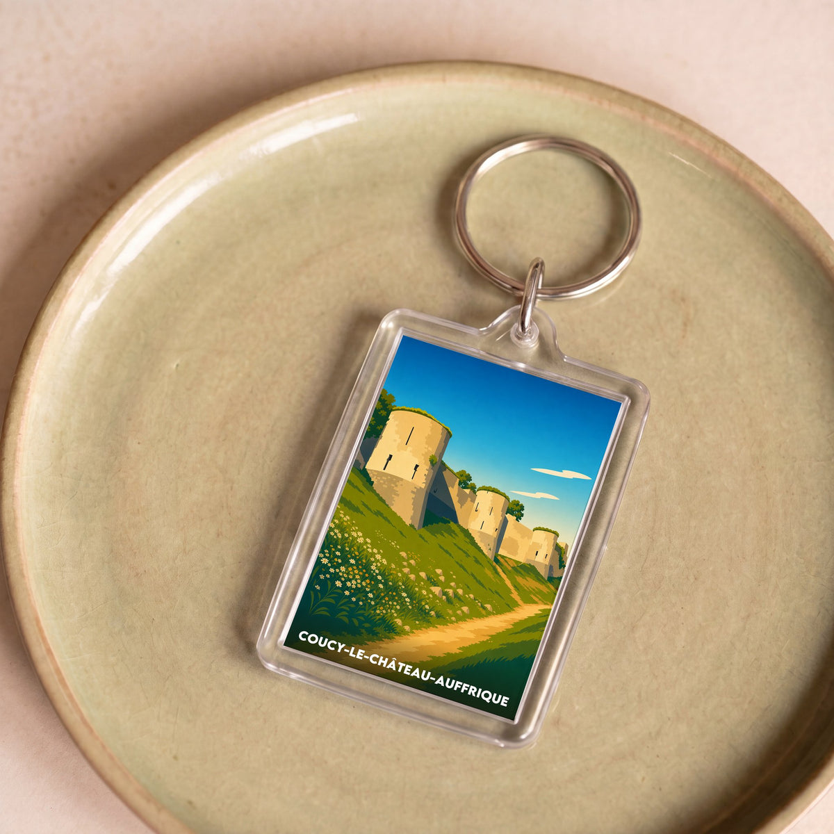 Porte-clés souvenir de la ville de Coucy-le-Château-Auffrique avec une illustration stylisée.