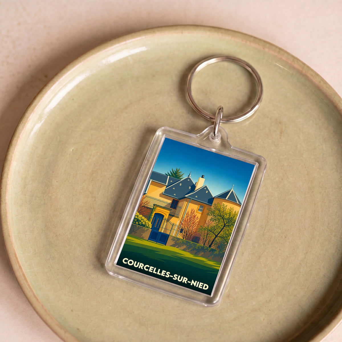 Porte-clés souvenir de la ville de Courcelles-sur-Nied avec une illustration stylisée.