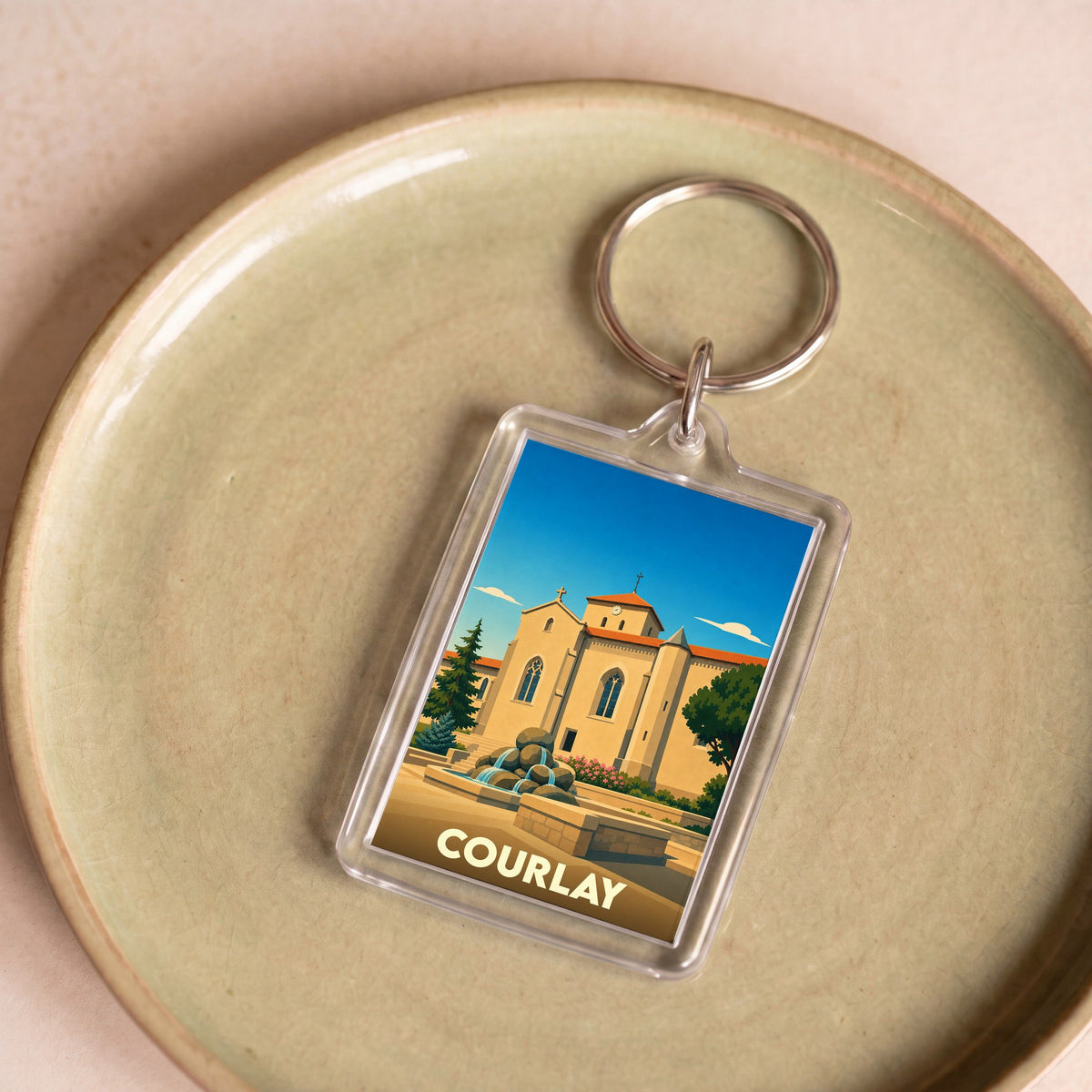 Porte-clés souvenir de la ville de Courlay avec une illustration stylisée d'une église et d'une fontaine.