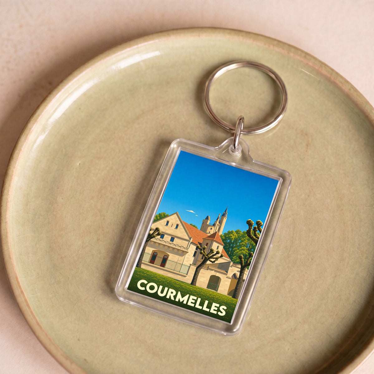 Porte-clés souvenir de la ville de Courmelles avec une illustration stylisée.