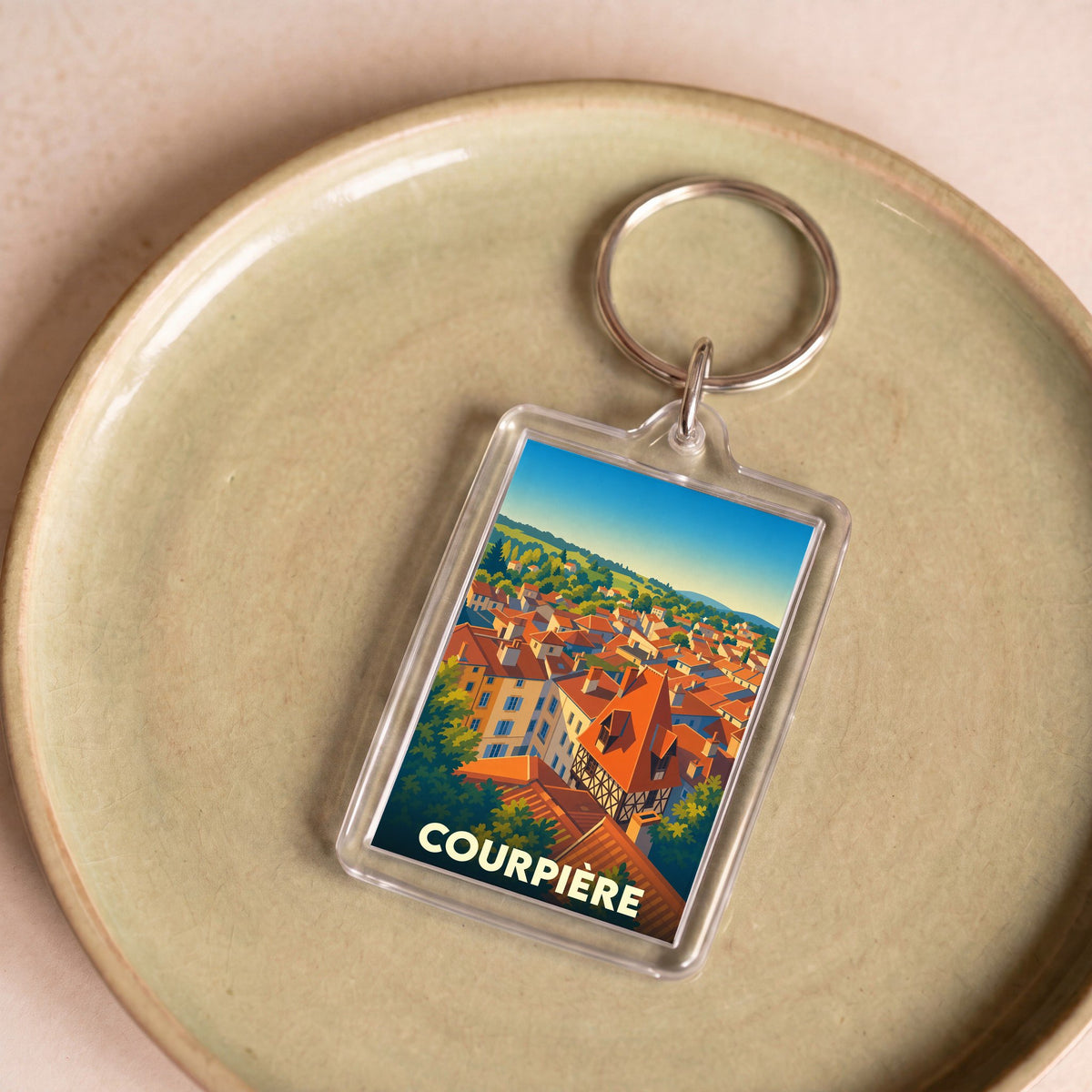 Porte-clés souvenir de la ville de Courpière avec une illustration stylisée.