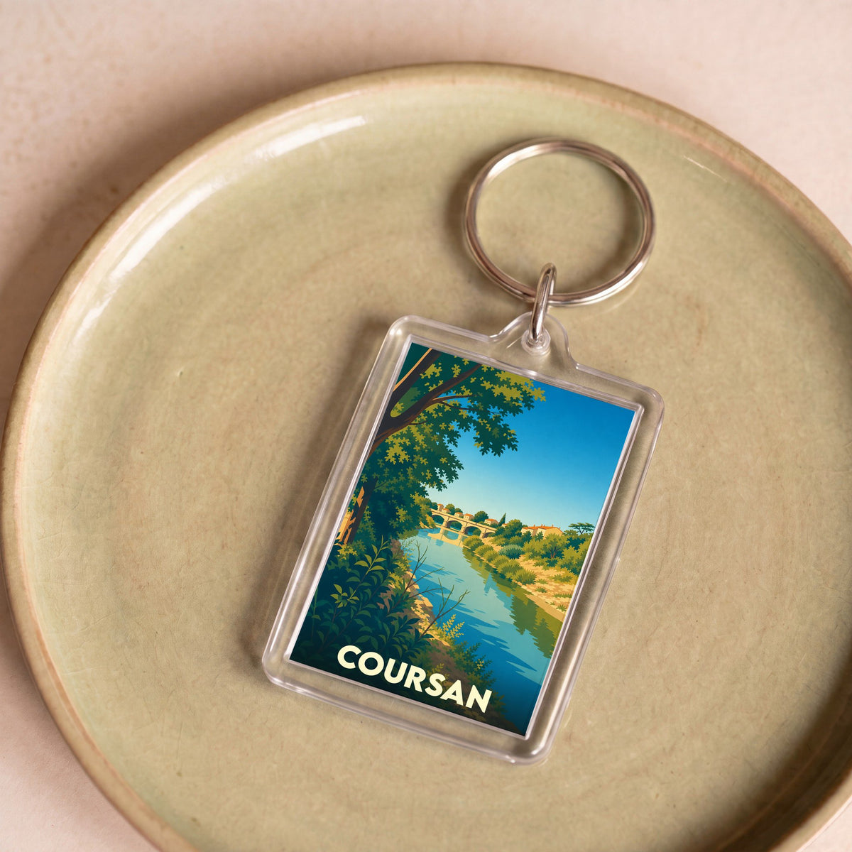 Porte-clés souvenir de la ville de Coursan avec une illustration stylisée représentant un pont sur une rivière.