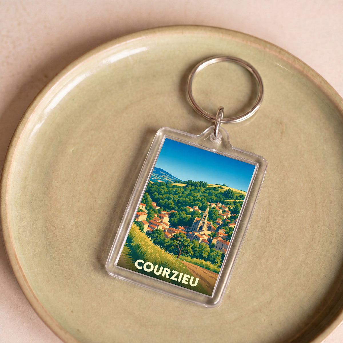 Porte-clés souvenir de la ville de Courzieu avec une illustration stylisée de son paysage vallonné.