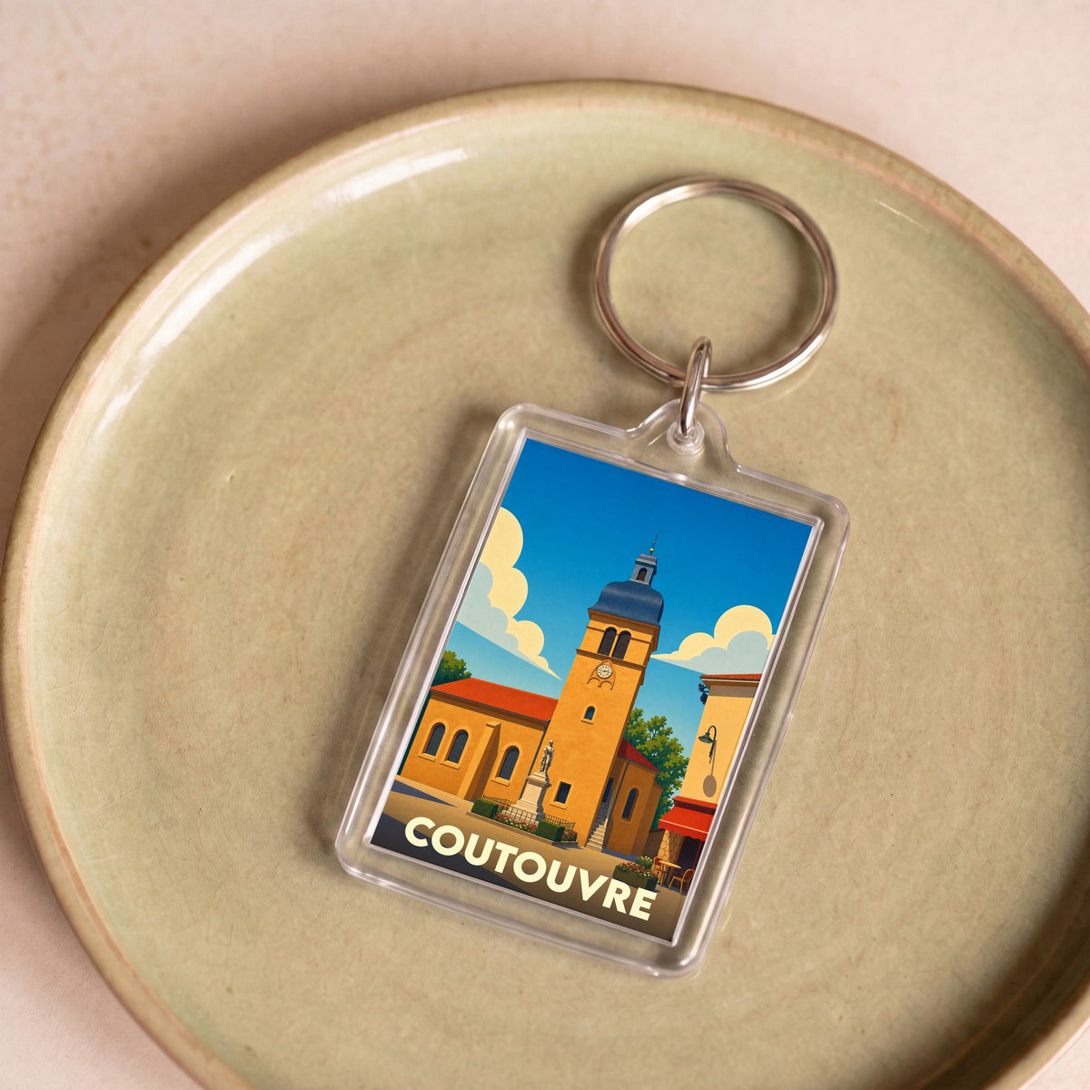 Porte-clés souvenir de la ville de Coutouvre avec une illustration stylisée de son église.