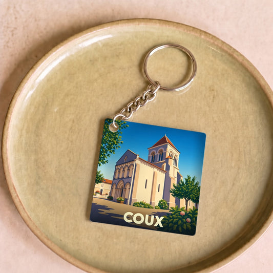 Porte-clés souvenir de la ville de Coux avec une illustration stylisée d'une église sous un ciel bleu.