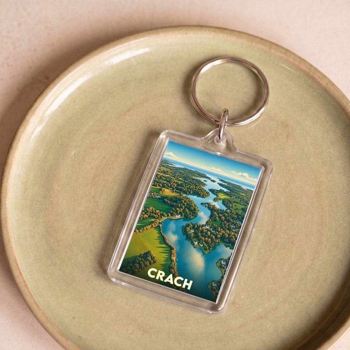 Porte-clés souvenir de la ville de Crach avec une illustration stylisée d'un paysage côtier vu du ciel.