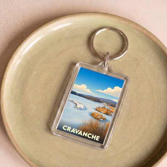 Porte-clés souvenir de la ville de Cravanche avec une illustration stylisée de paysage hivernal.
