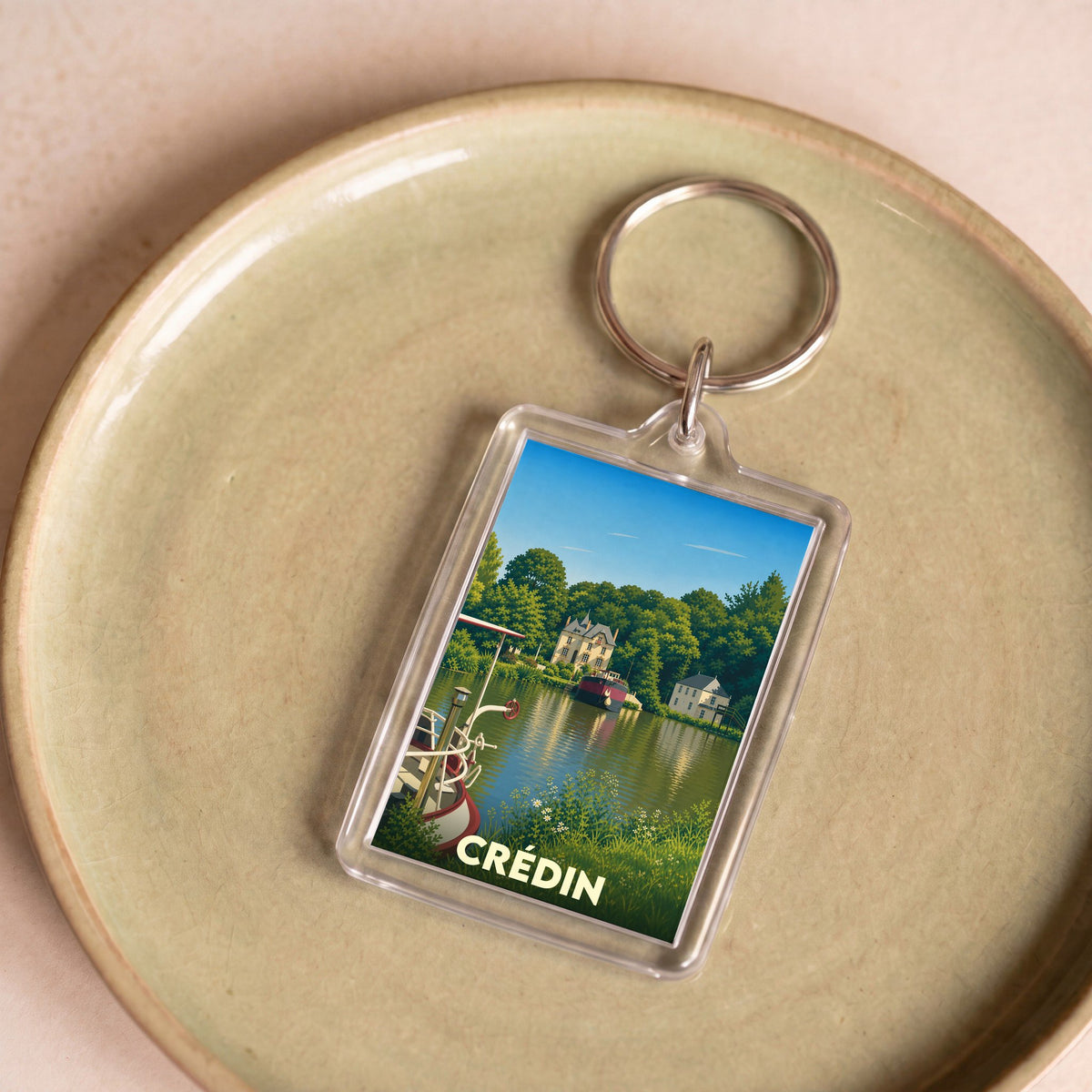 Porte-clés souvenir de la ville de Crédin avec une illustration stylisée d'un paysage fluvial.