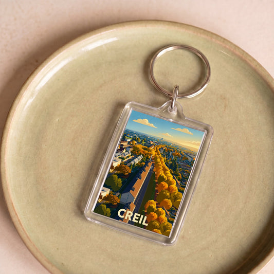 Porte-clés souvenir de la ville de Creil avec une illustration stylisée d'un paysage urbain.