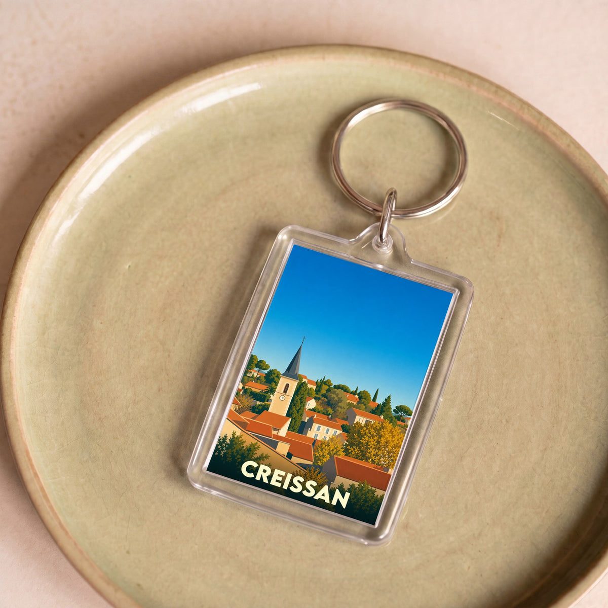 Porte-clés souvenir de la ville de Creissan avec une illustration stylisée.