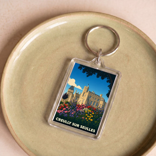 Porte-clés souvenir de la ville de Creully sur Seulles avec une illustration stylisée de son château et de jardins fleuris.