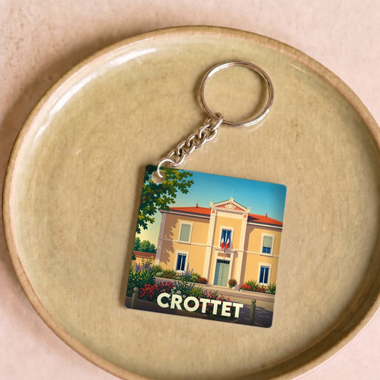 Porte-clés souvenir de la ville de Crottet avec une illustration stylisée de sa mairie.