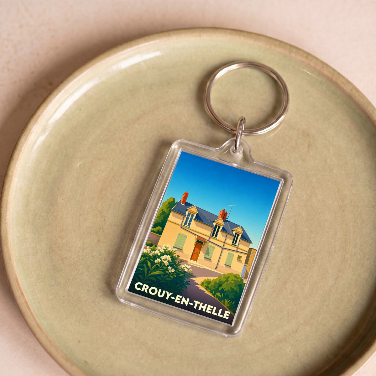 Porte-clés souvenir de la ville de Crouy-en-Thelle avec une illustration stylisée d'une maison traditionnelle.