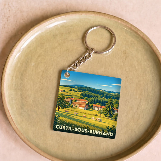Porte-clés souvenir de la ville de Curtil-sous-Burnand avec une illustration stylisée de paysages vallonnés.