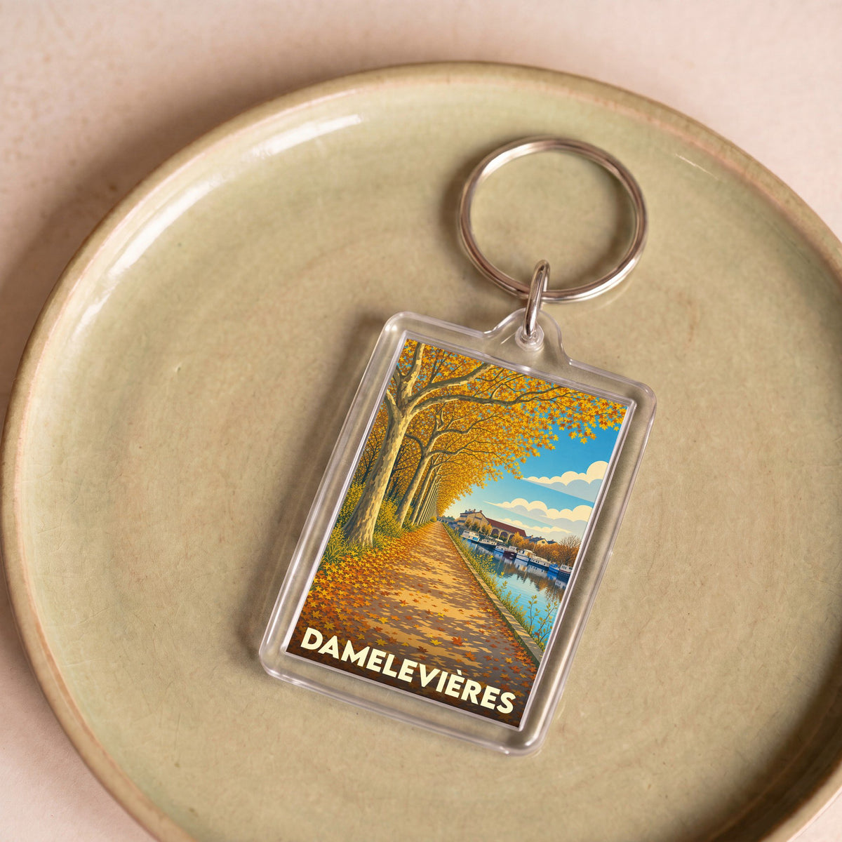 Porte-clés souvenir de la ville de Damelevières avec une illustration stylisée d'un canal en automne.