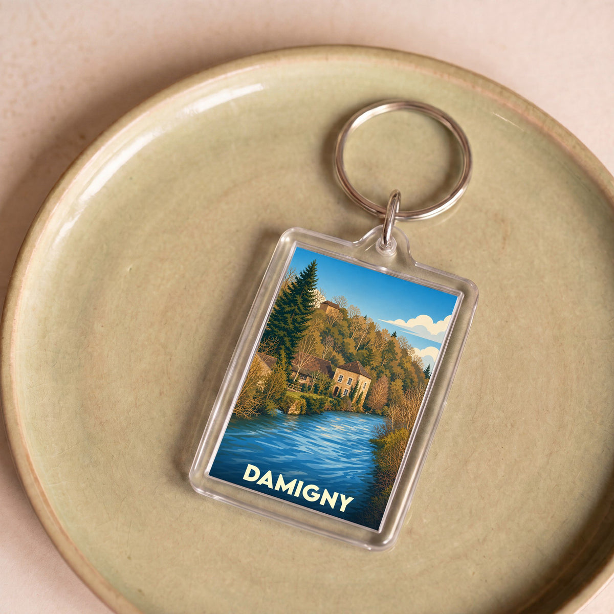 Porte-clés souvenir de la ville de Damigny avec une illustration stylisée d'un paysage fluvial.