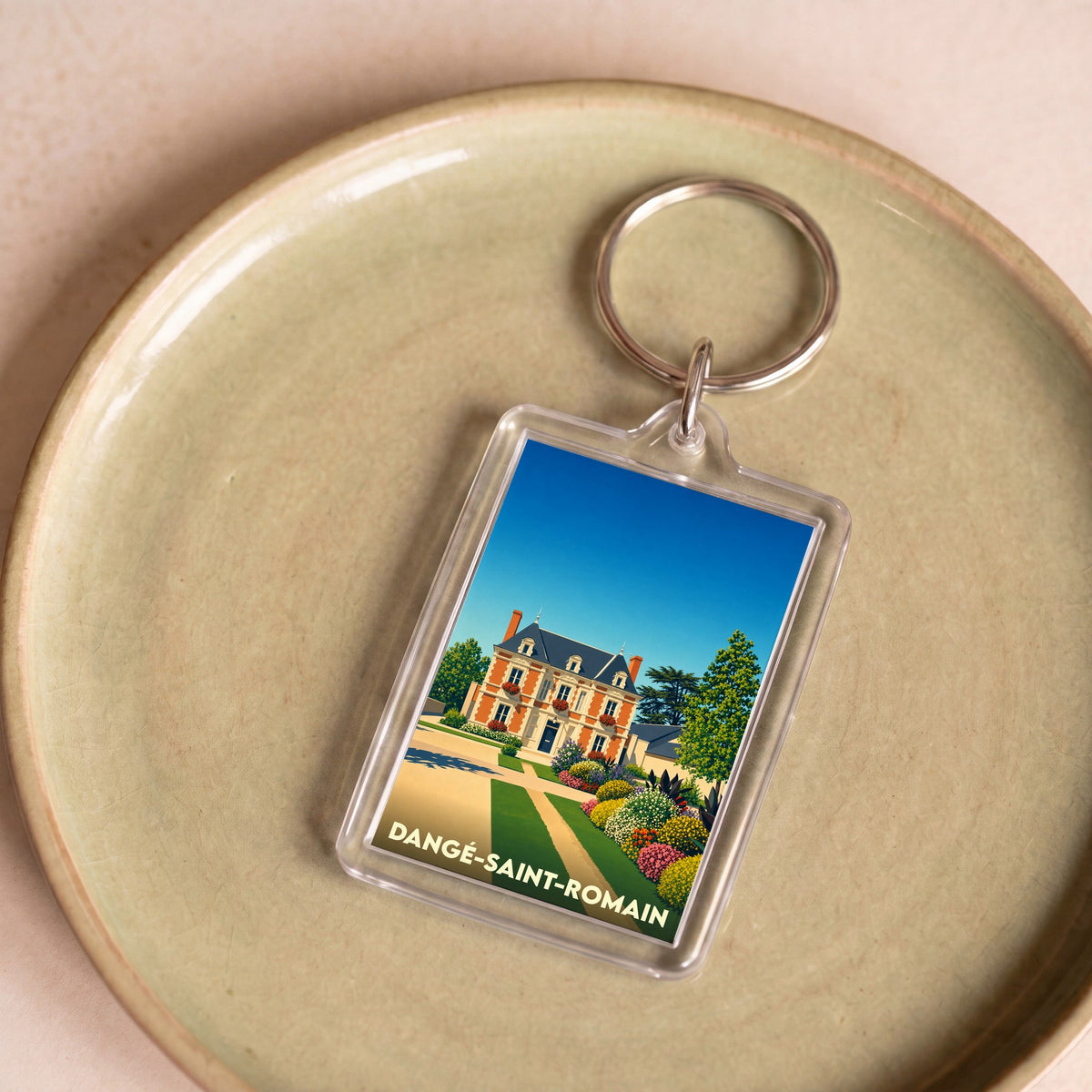 Porte-clés souvenir de la ville de Dangé-Saint-Romain avec une illustration stylisée d'un manoir fleuri.