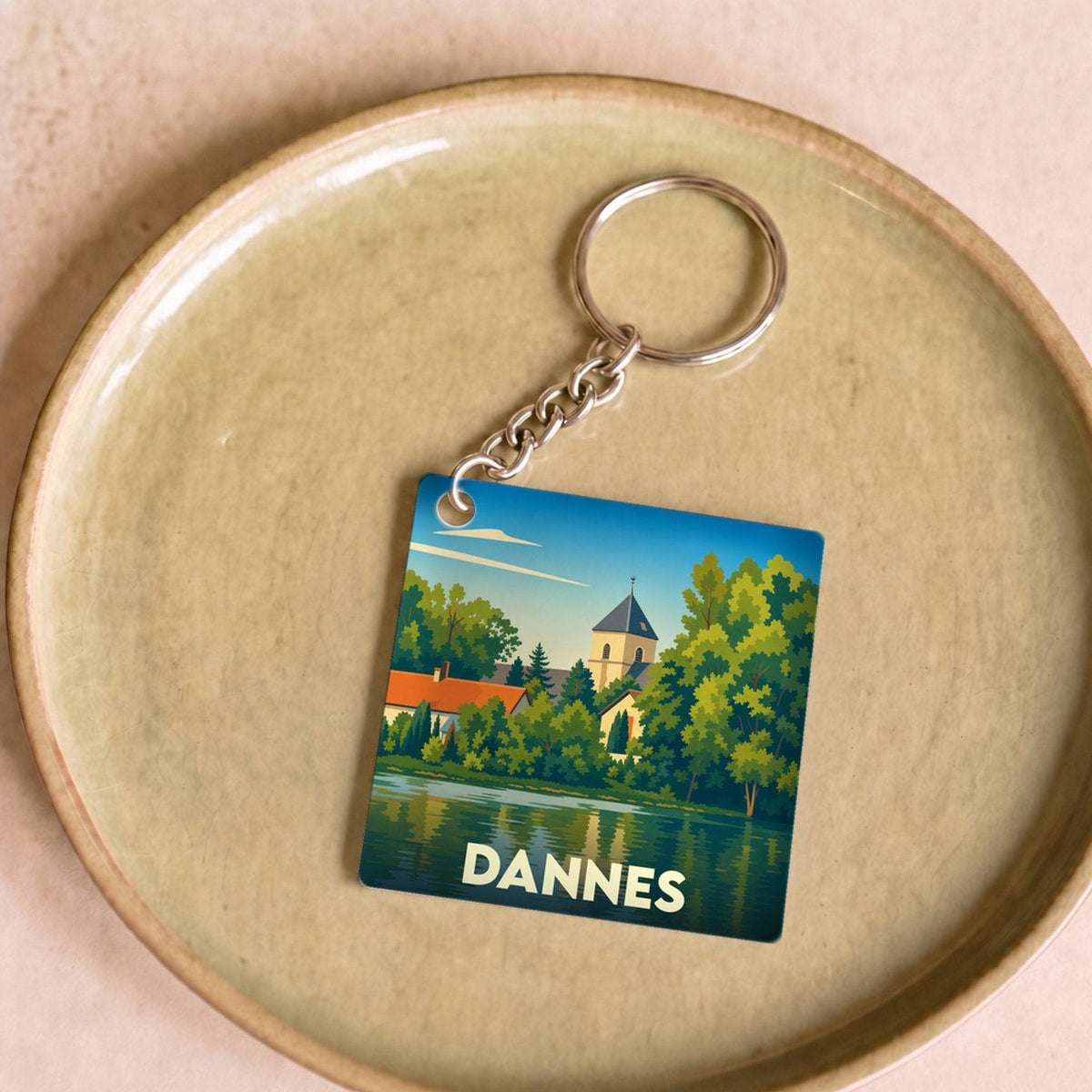 Porte-clés souvenir de la ville de Dannes avec une illustration stylisée d'un paysage au bord de l'eau.