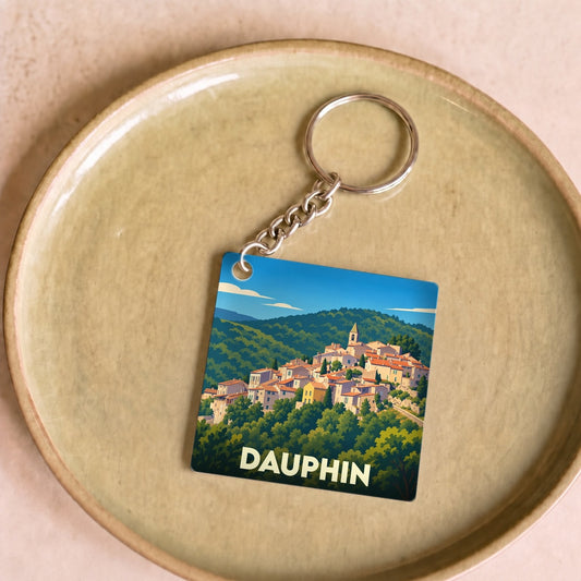 Porte-clés souvenir de la ville de Dauphin avec une illustration stylisée d'un village perché.