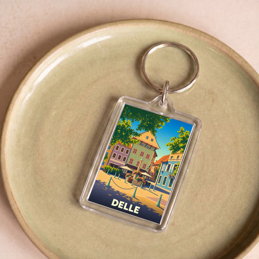Porte-clés souvenir de la ville de Delle avec une illustration stylisée d'une place colorée.
