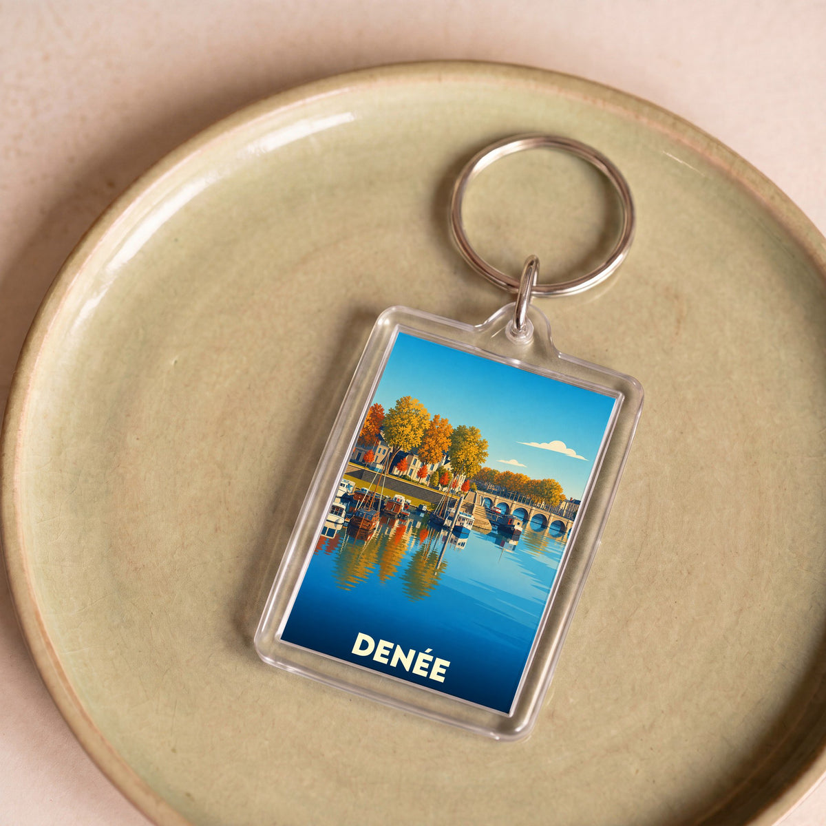 Porte-clés souvenir de la ville de Denée avec une illustration stylisée des bords de l'eau.