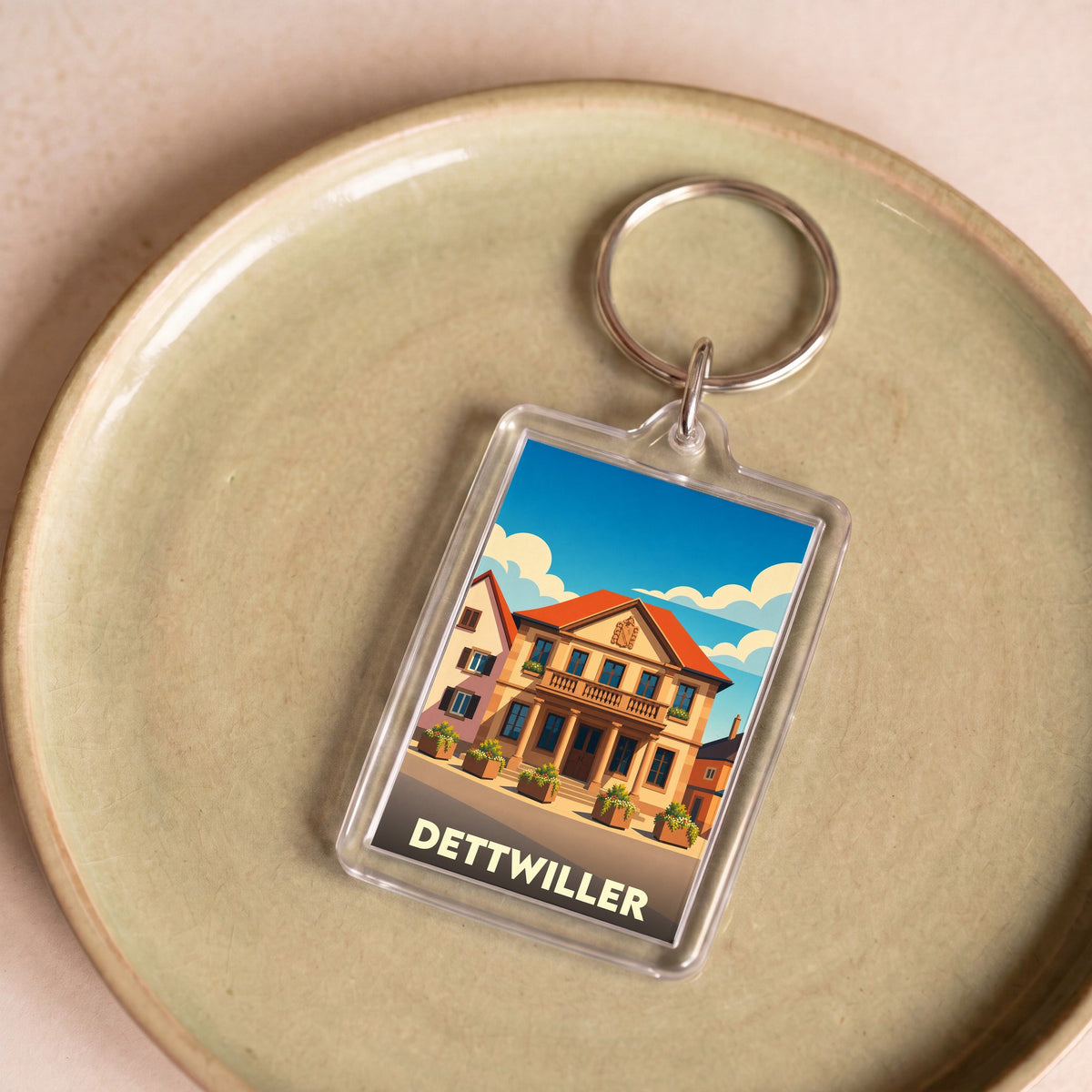 Porte-clés souvenir de la ville de Dettwiller avec une illustration stylisée de son architecture.