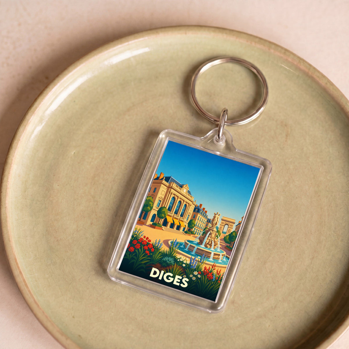 Porte-clés souvenir de la ville de Diges avec une illustration stylisée d'une place ensoleillée.