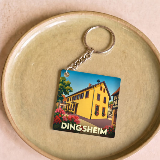 Porte-clés souvenir de la ville de Dingsheim avec une illustration stylisée d'une maison alsacienne.
