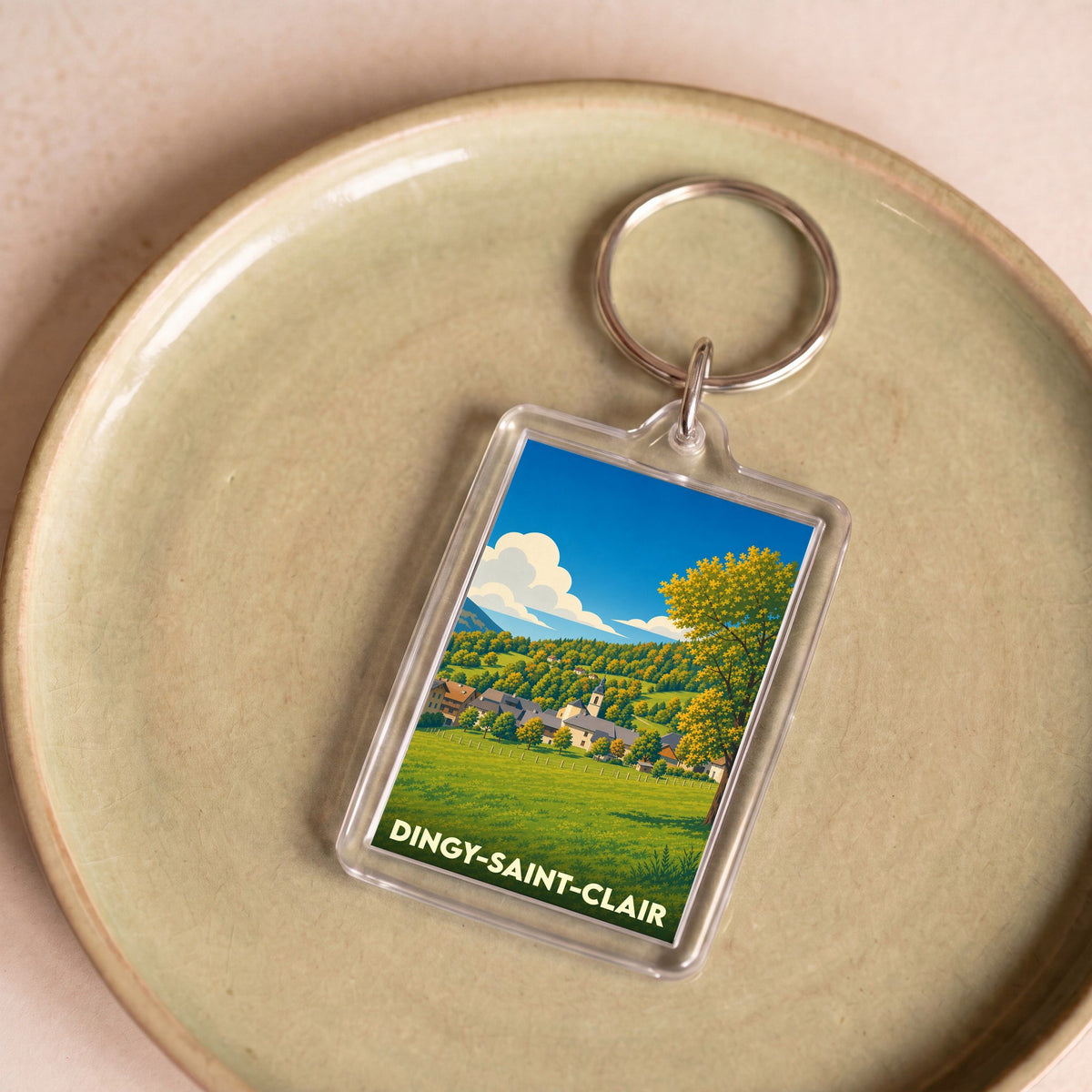 Porte-clés souvenir de la ville de Dingy-Saint-Clair avec une illustration stylisée de son paysage champêtre.