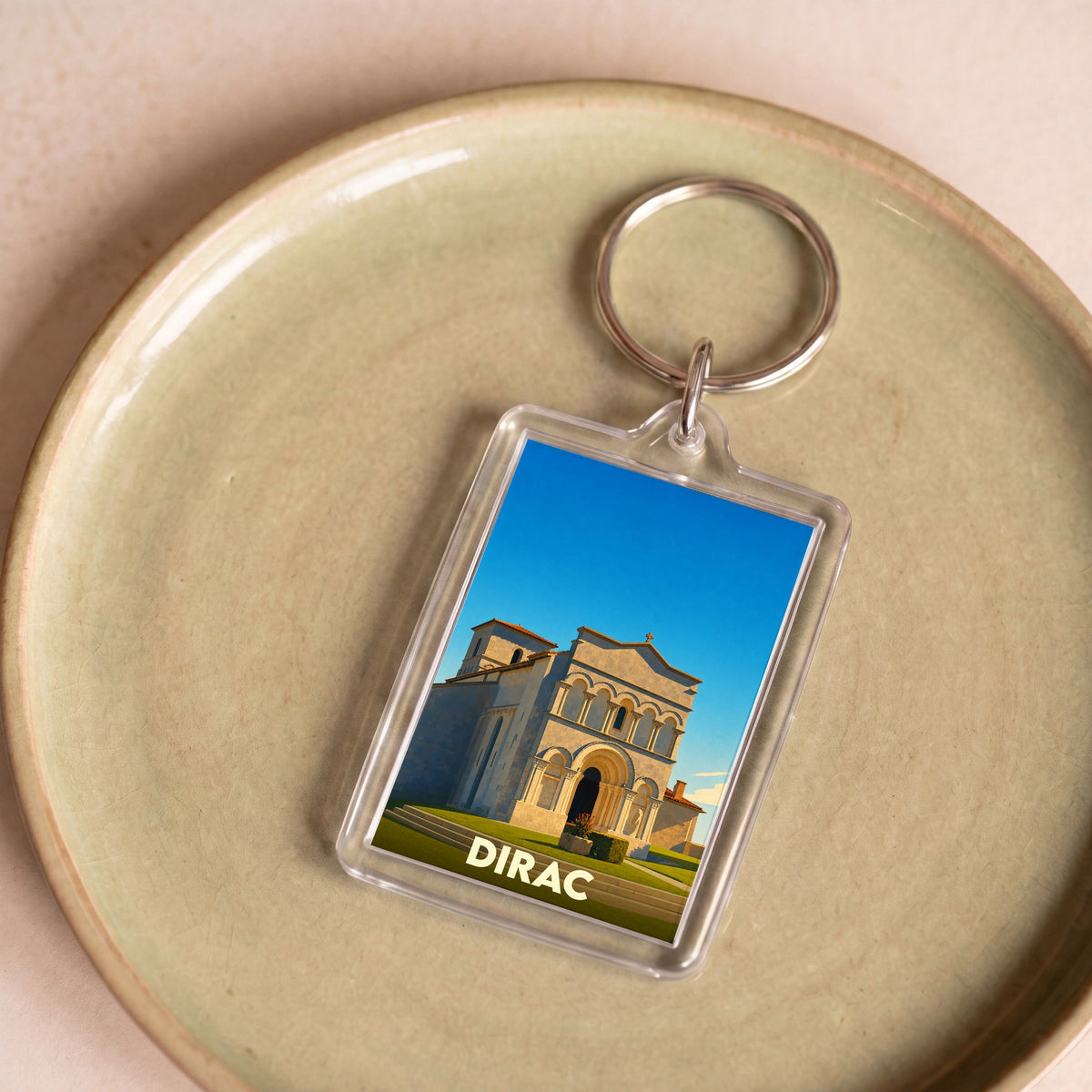 Porte-clés souvenir de la ville de Dirac avec une illustration stylisée de son église romane.
