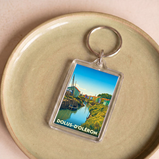 Porte-clés souvenir de la ville de Dolus-d'Oléron avec une illustration stylisée de cabanes colorées au bord de l'eau.