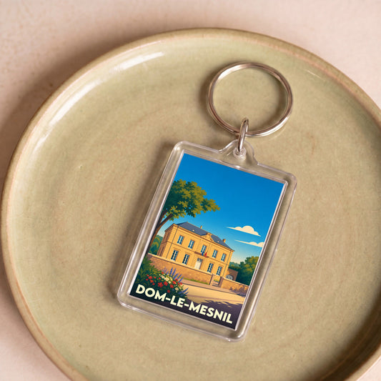 Porte-clés souvenir de la ville de Dom-le-Mesnil avec une illustration stylisée de sa mairie.