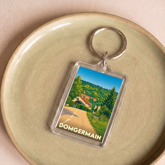 Porte-clés souvenir de la ville de Domgermain avec une illustration stylisée d'un paysage vallonné.