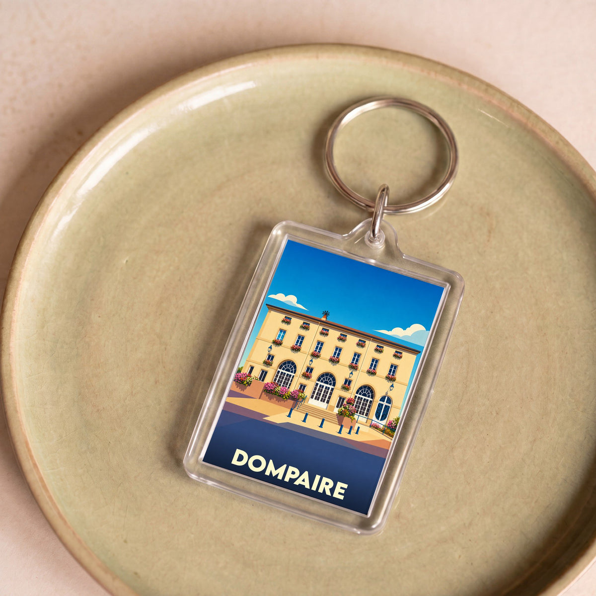 Porte-clés souvenir de la ville de Dompaire avec une illustration stylisée de son architecture.