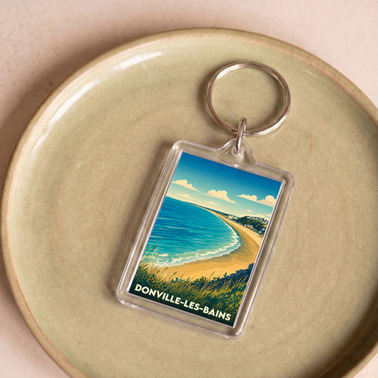 Porte-clés souvenir de la ville de Donville-les-Bains avec une illustration stylisée de sa plage.