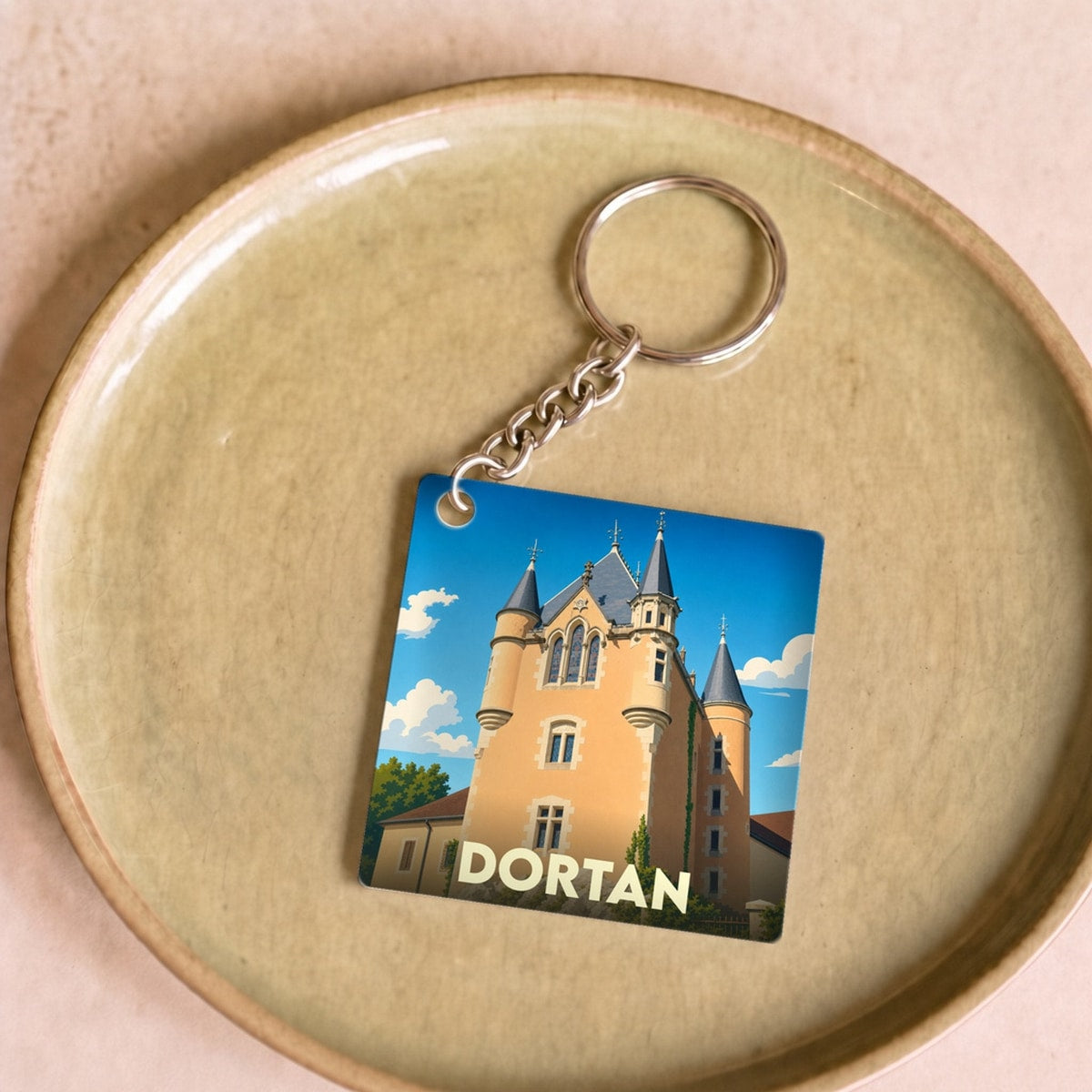 Porte-clés souvenir de la ville de Dortan avec une illustration stylisée de son château.