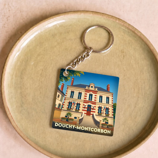 Porte-clés souvenir de la ville de Douchy-Montcorbon avec une illustration stylisée de sa mairie.