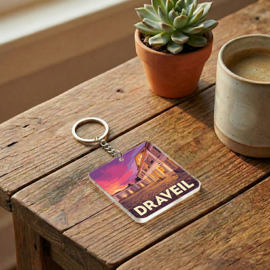 Porte-clés souvenir de la ville de Draveil avec une illustration stylisée d'un bâtiment au coucher du soleil.