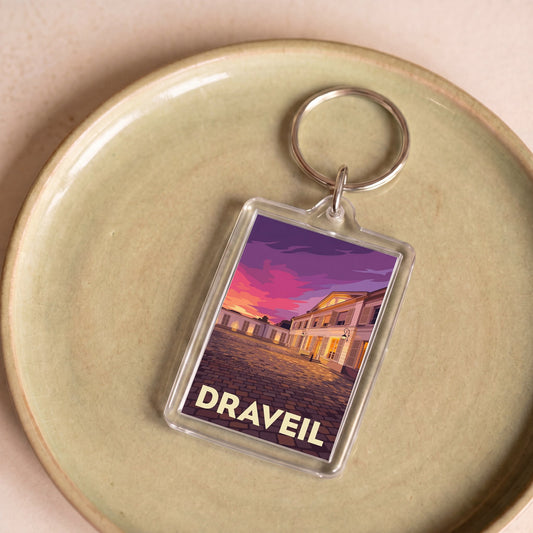 Porte-clés souvenir de la ville de Draveil avec une illustration stylisée d'un bâtiment au coucher du soleil.