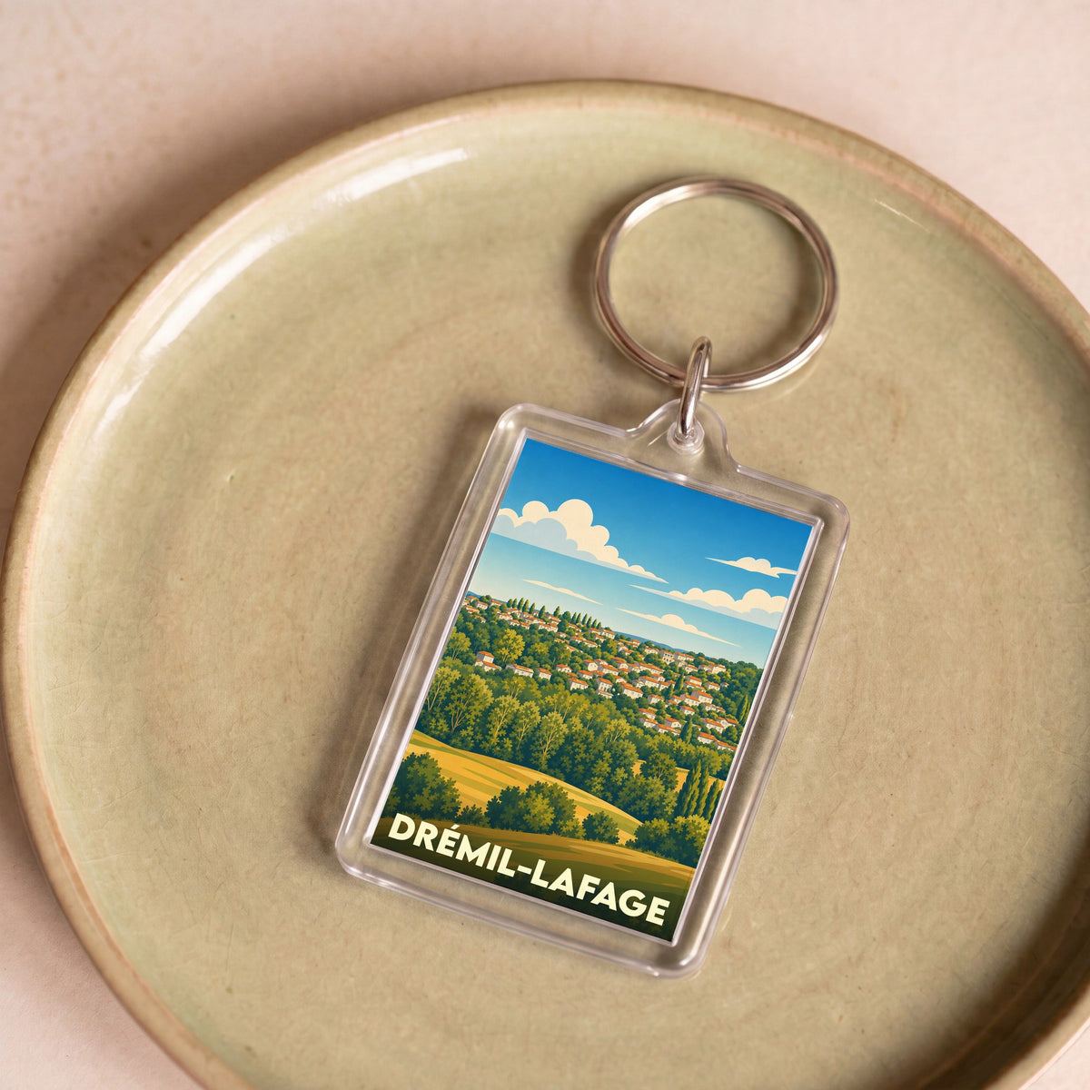 Porte-clés souvenir de la ville de Drémil-Lafage avec une illustration stylisée d'un paysage vallonné.