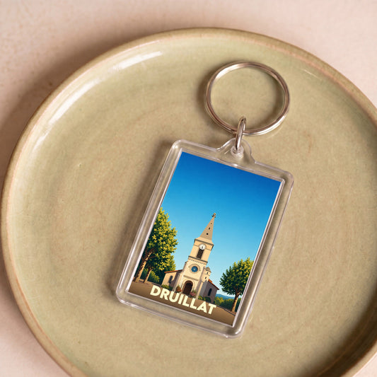 Porte-clés souvenir de la ville de Druillat avec une illustration stylisée d'une église sous un ciel bleu.