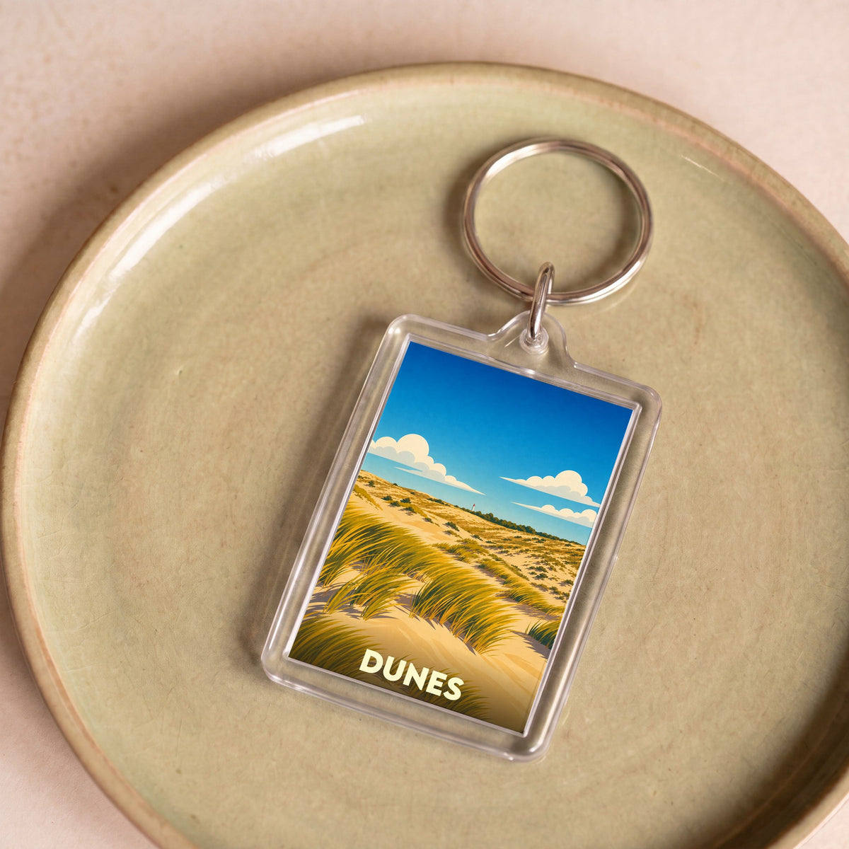 Porte-clés souvenir de la ville de Dunes avec une illustration stylisée de paysages dunaires.