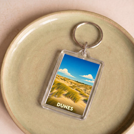Porte-clés souvenir de la ville de Dunes avec une illustration stylisée de paysages dunaires.