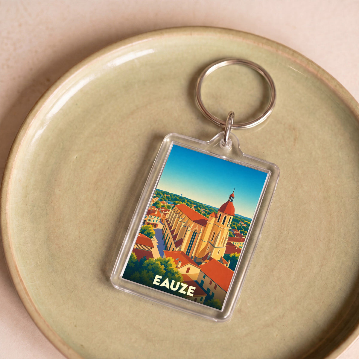 Porte-clés souvenir de la ville d'Eauze avec une illustration stylisée de son église et de ses toits.