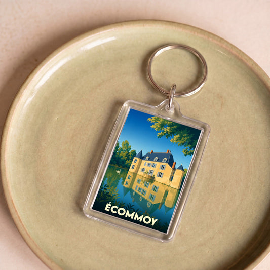 Porte-clés souvenir de la ville d'Écommoy avec une illustration stylisée d'un château se reflétant dans l'eau.